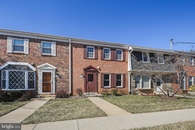 view of property featuring a front yard and brick siding