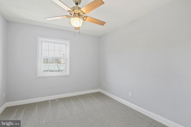 spare room with carpet floors, baseboards, visible vents, and a ceiling fan