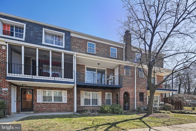 townhome / multi-family property featuring brick siding, a chimney, and a front lawn