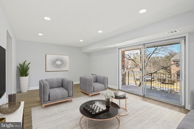 living area featuring recessed lighting, visible vents, baseboards, and wood finished floors