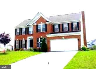 colonial house featuring driveway, a garage, and a front yard