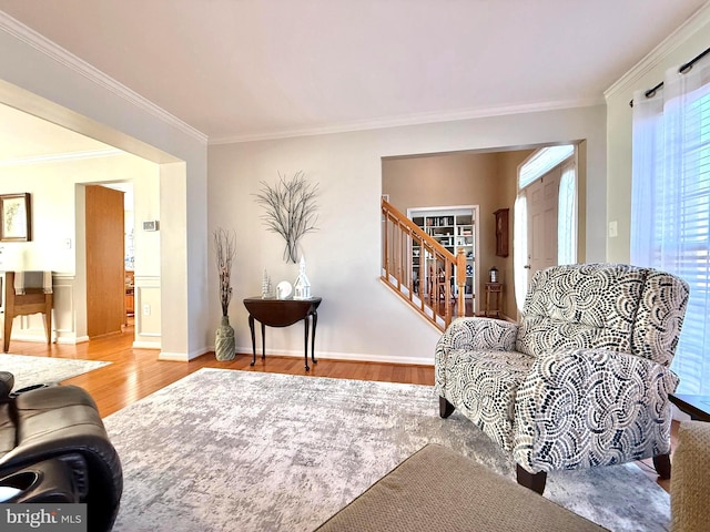 living area with crown molding, stairs, baseboards, and wood finished floors