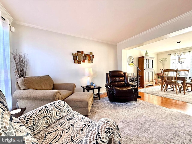 living room with a notable chandelier, wood finished floors, and crown molding