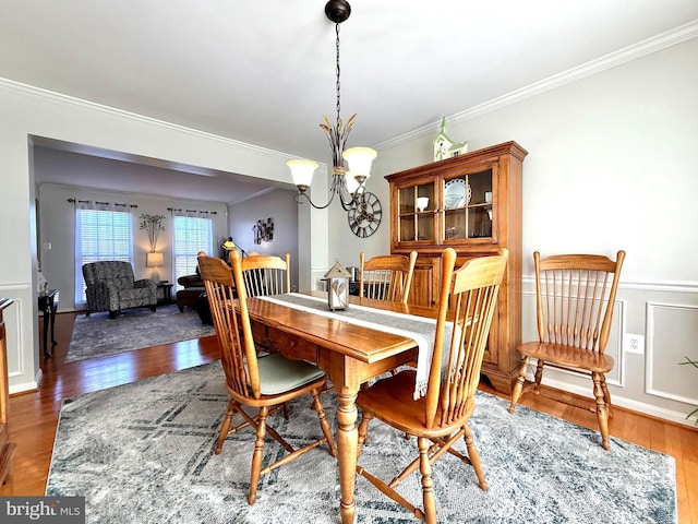 dining space with crown molding, wood finished floors, and a chandelier