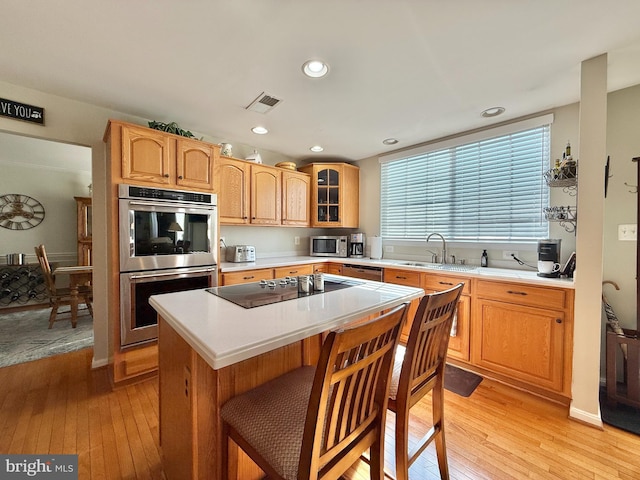 kitchen featuring visible vents, light wood-style flooring, stainless steel appliances, light countertops, and glass insert cabinets