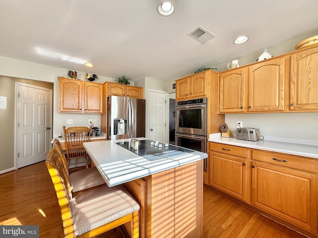 kitchen featuring a breakfast bar area, visible vents, a kitchen island, stainless steel appliances, and light countertops