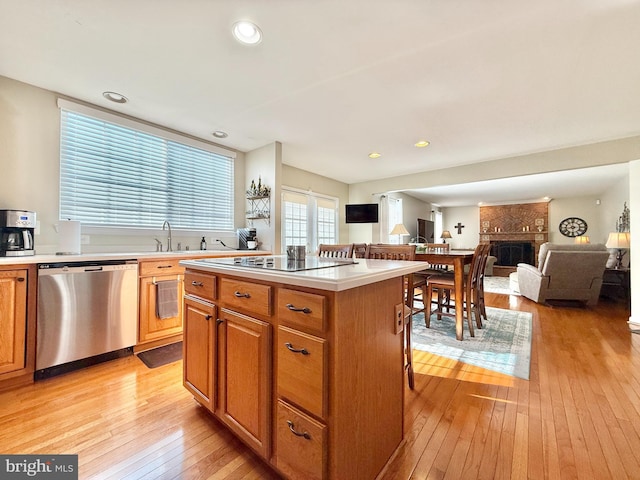 kitchen with stainless steel dishwasher, a center island, a large fireplace, light countertops, and black electric stovetop