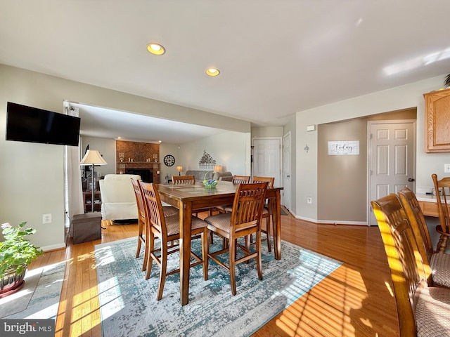 dining room featuring baseboards, light wood-style floors, and a fireplace