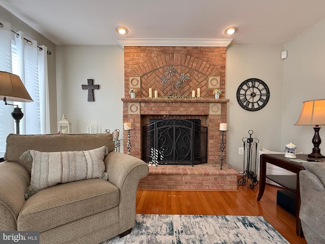 living room featuring a brick fireplace and wood finished floors