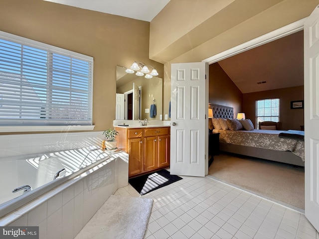 ensuite bathroom featuring connected bathroom, tile patterned floors, lofted ceiling, a bath, and vanity