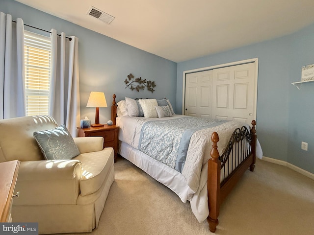 bedroom featuring light colored carpet, visible vents, a closet, and baseboards