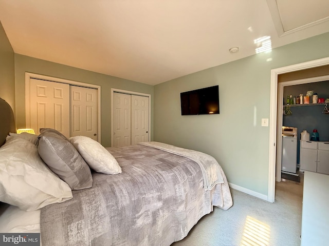 bedroom featuring carpet flooring, two closets, baseboards, and separate washer and dryer