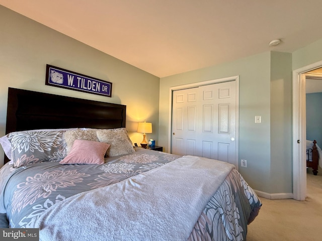 carpeted bedroom with a closet, baseboards, and lofted ceiling