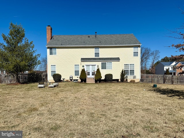 back of house featuring a lawn, entry steps, a chimney, and fence