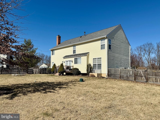 back of house featuring a lawn, a chimney, and fence