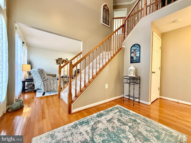 staircase featuring a high ceiling, baseboards, and hardwood / wood-style floors