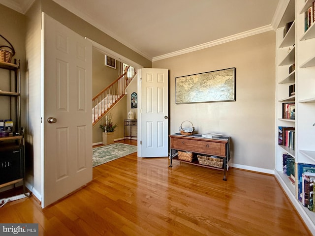 sitting room with visible vents, crown molding, light wood finished floors, baseboards, and stairs