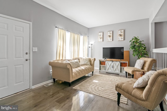 living room featuring wood finished floors, visible vents, and baseboards