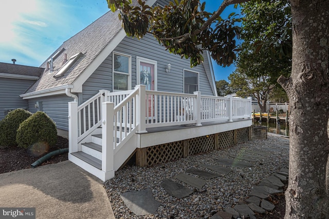 rear view of house featuring a wooden deck and roof with shingles