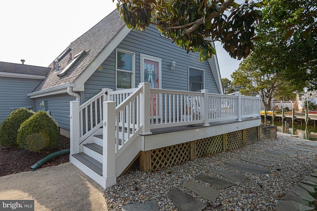 rear view of property with a wooden deck and a shingled roof