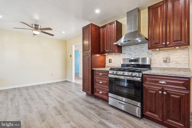 kitchen with stainless steel gas range oven, light wood-type flooring, backsplash, and wall chimney exhaust hood