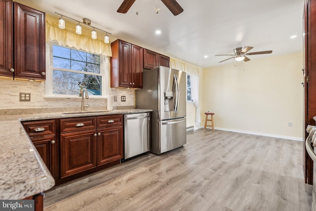 kitchen with backsplash, ceiling fan, light wood-style floors, stainless steel appliances, and a sink