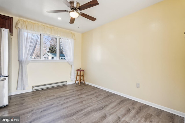 unfurnished room featuring wood finished floors, baseboards, baseboard heating, and ceiling fan