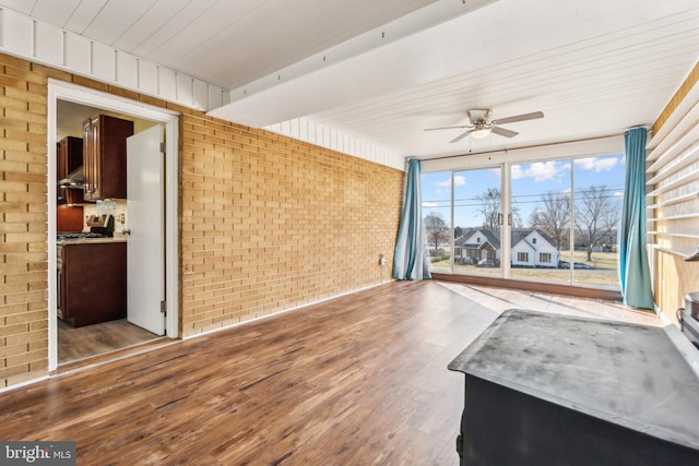 interior space featuring wood ceiling, wood finished floors, brick wall, and ceiling fan