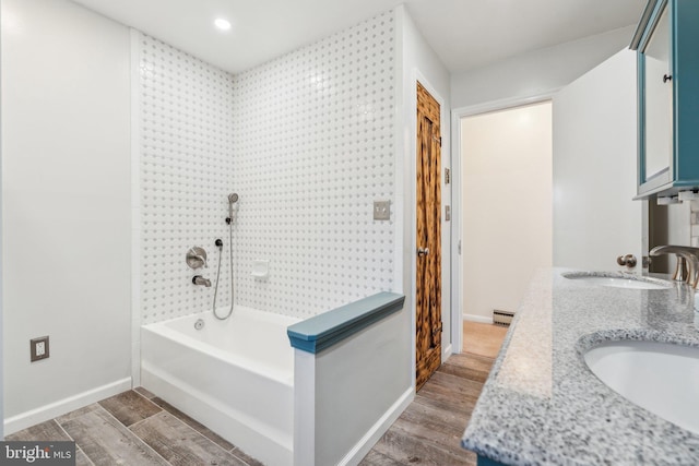 bathroom featuring a sink, a baseboard radiator, baseboards, and wood finished floors