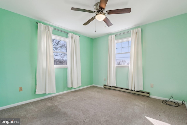 carpeted empty room featuring a baseboard heating unit, a healthy amount of sunlight, baseboards, and ceiling fan