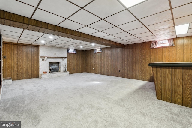 basement featuring a brick fireplace, carpet flooring, and wood walls