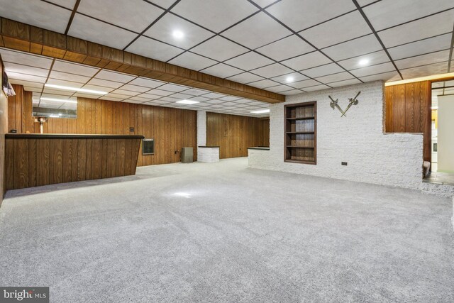 finished basement with wooden walls, a dry bar, and carpet