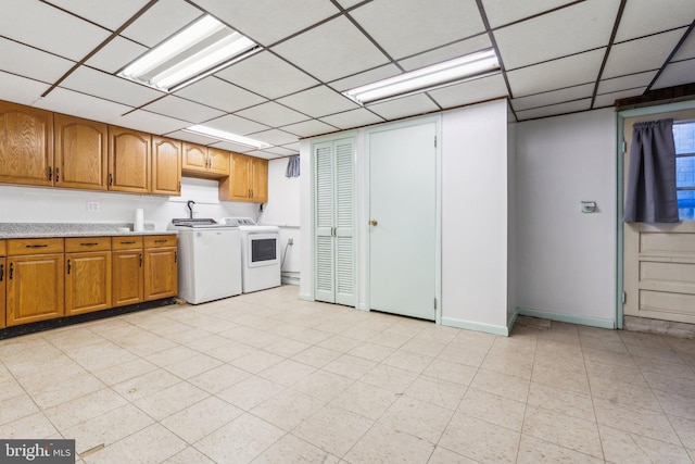 kitchen with light countertops, a paneled ceiling, independent washer and dryer, and brown cabinets