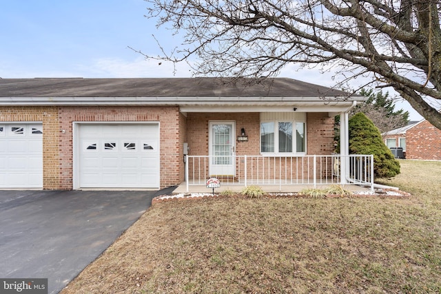 view of front of house with an attached garage, covered porch, aphalt driveway, and brick siding