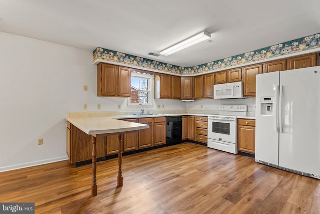 kitchen with light countertops, visible vents, light wood-style flooring, a sink, and white appliances