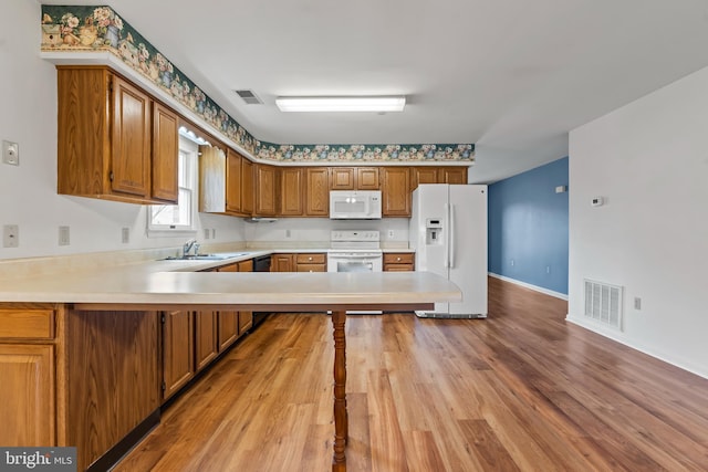 kitchen featuring light countertops, white appliances, visible vents, and brown cabinets