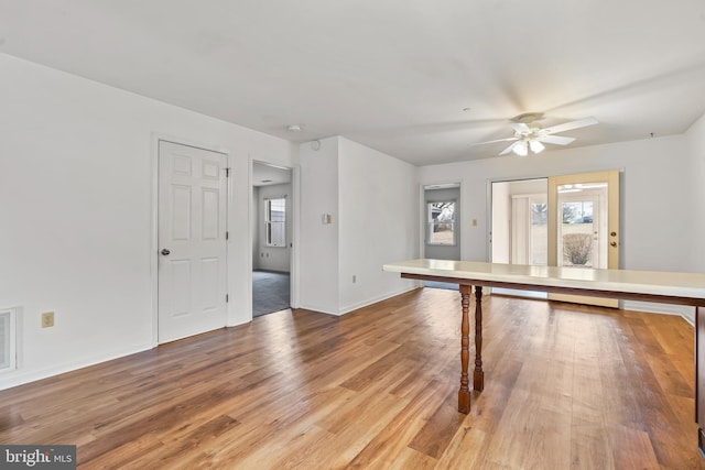 interior space with a ceiling fan, visible vents, baseboards, and wood finished floors