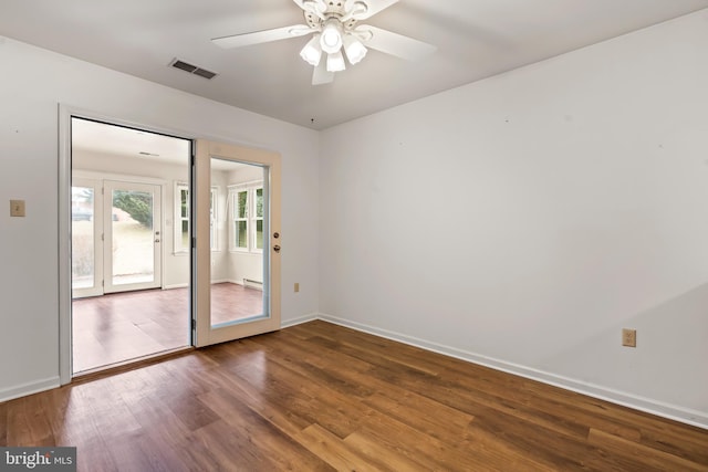 unfurnished room with a ceiling fan, visible vents, baseboards, and wood finished floors