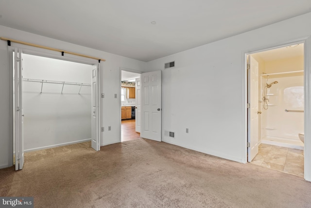 unfurnished bedroom with light colored carpet, a closet, visible vents, and ensuite bath