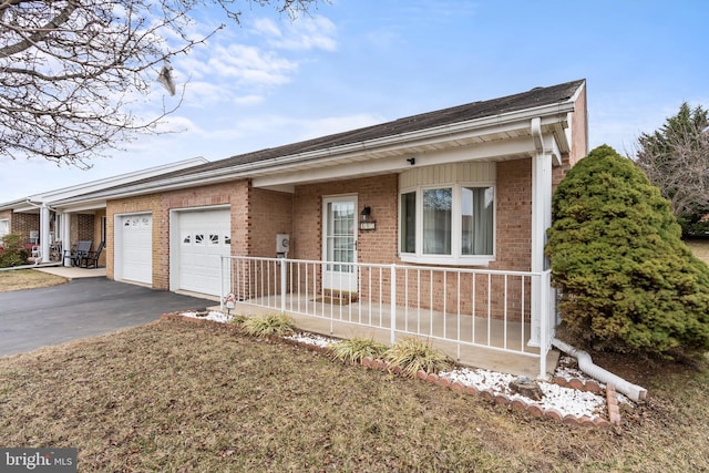 ranch-style home with a garage, driveway, brick siding, and covered porch