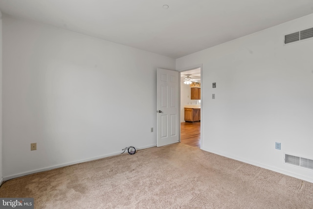 spare room featuring carpet, visible vents, and baseboards