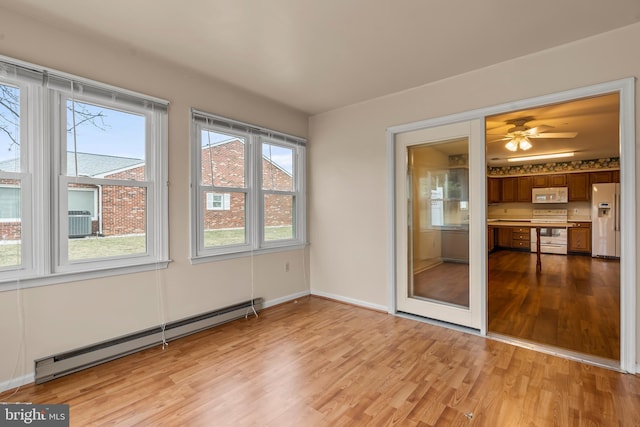 unfurnished sunroom featuring baseboard heating and a ceiling fan