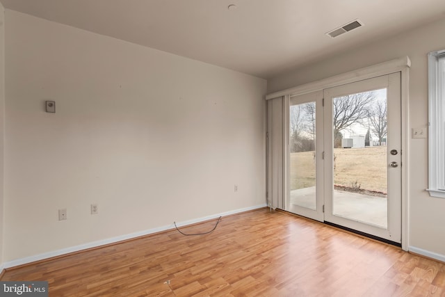 doorway with light wood-type flooring, visible vents, and baseboards