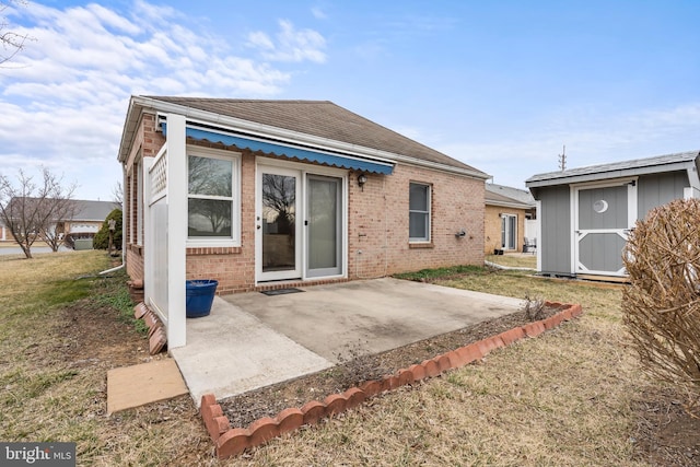 back of property featuring brick siding, a lawn, a storage shed, a patio area, and an outdoor structure