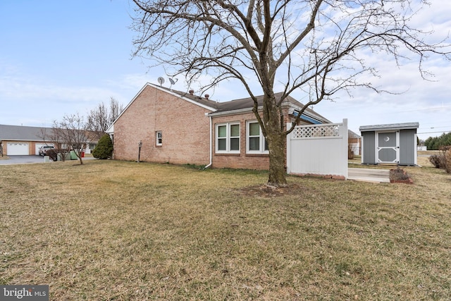 view of property exterior featuring an outbuilding, brick siding, fence, a yard, and a shed