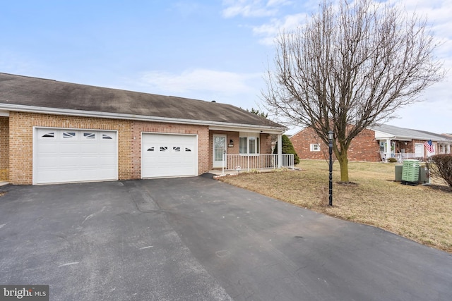 single story home featuring driveway, covered porch, an attached garage, and brick siding