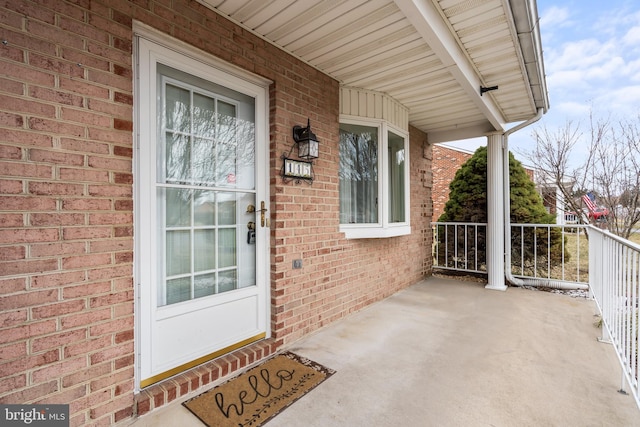 doorway to property with covered porch and brick siding