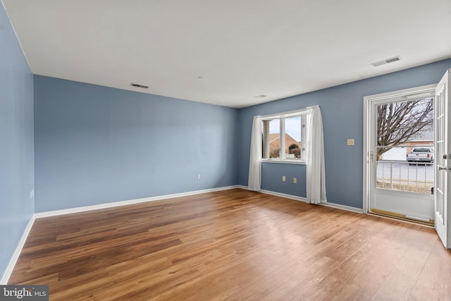 spare room featuring visible vents, baseboards, and wood finished floors