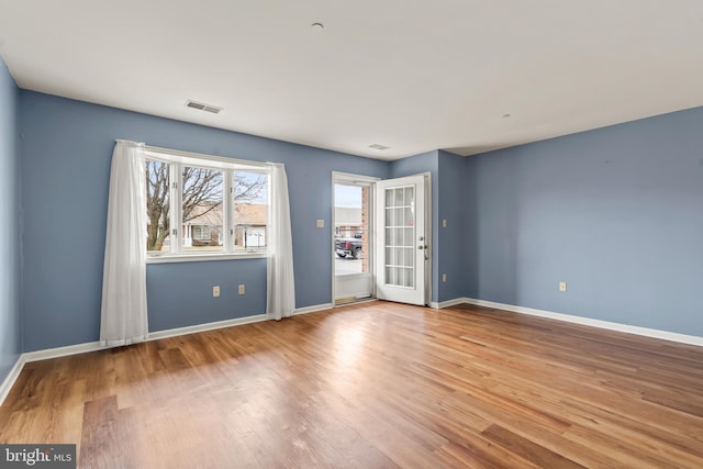 empty room with visible vents, baseboards, and wood finished floors