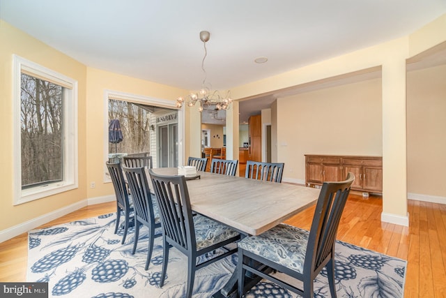 dining room with baseboards, a notable chandelier, and light wood finished floors